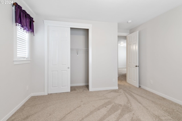 unfurnished bedroom with light colored carpet and a closet