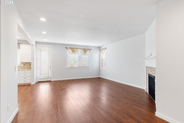 unfurnished living room featuring a tile fireplace and dark wood-type flooring