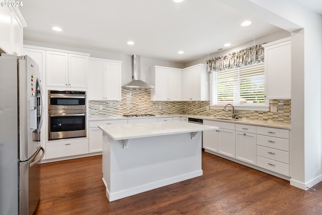 kitchen with white cabinets, a kitchen island, wall chimney exhaust hood, dark wood-type flooring, and stainless steel appliances