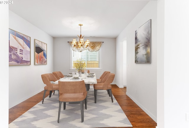 dining area with hardwood / wood-style floors and a chandelier