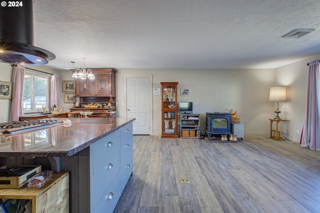 kitchen featuring pendant lighting, stainless steel gas cooktop, light hardwood / wood-style flooring, and a textured ceiling