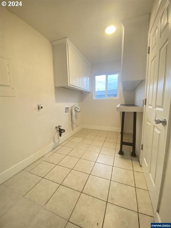 laundry room featuring washer hookup, light tile patterned floors, and cabinets