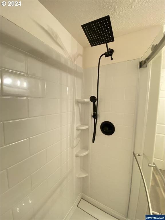 bathroom featuring tiled shower and a textured ceiling