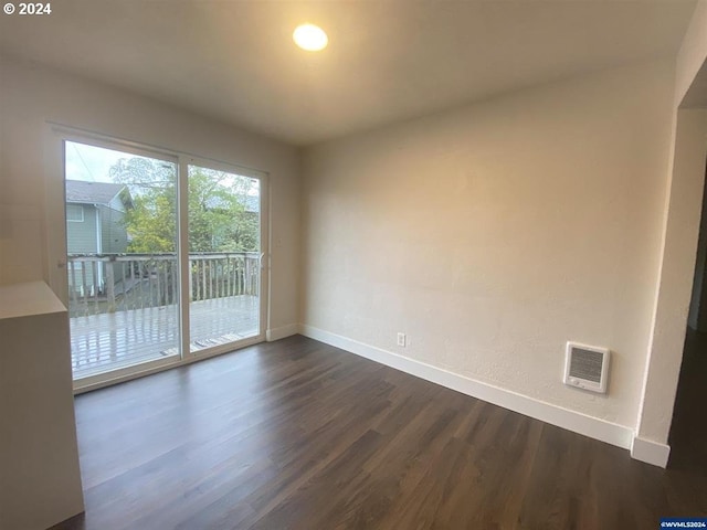 spare room with heating unit and dark hardwood / wood-style flooring