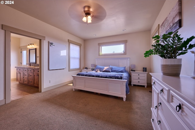 bedroom featuring ensuite bath, sink, light colored carpet, and ceiling fan