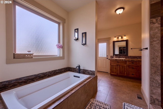 bathroom with vanity, a relaxing tiled tub, and tile patterned floors