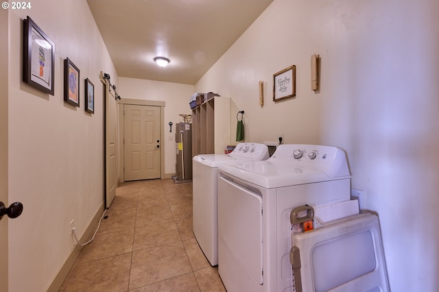 laundry room with washer and dryer, a barn door, electric water heater, and light tile patterned floors