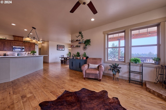 living room featuring sink, light hardwood / wood-style floors, and ceiling fan