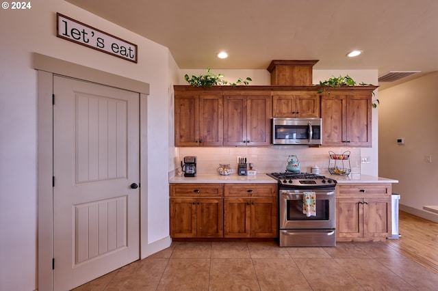 kitchen featuring appliances with stainless steel finishes, light wood-type flooring, and tasteful backsplash