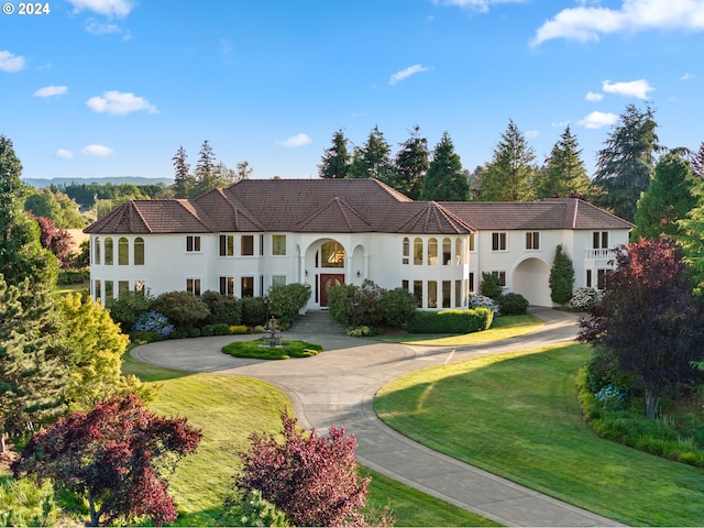 mediterranean / spanish house with curved driveway, a front lawn, and stucco siding