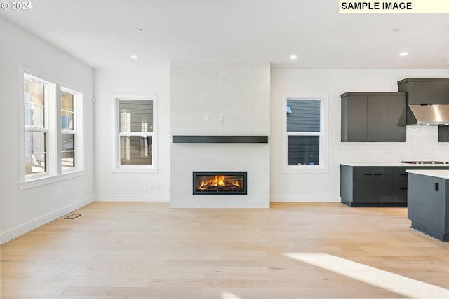 unfurnished living room with light wood-type flooring, baseboards, recessed lighting, and a fireplace