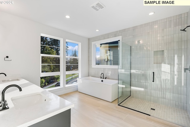 full bath with a stall shower, a soaking tub, recessed lighting, double vanity, and tile walls