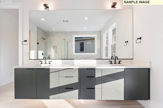 full bathroom with a tile shower, double vanity, and recessed lighting