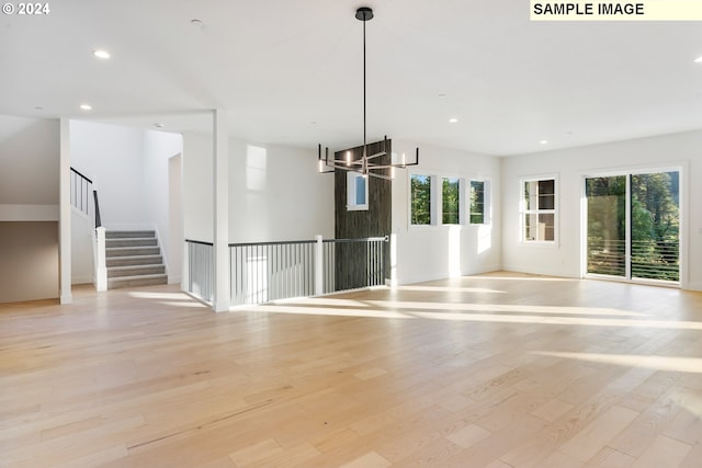 unfurnished living room with light wood-style floors, recessed lighting, a chandelier, stairway, and baseboards