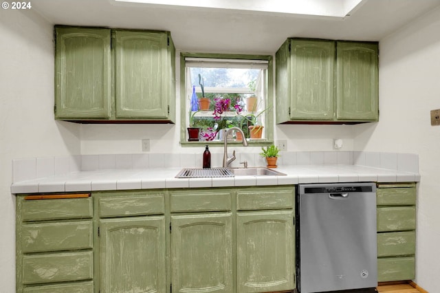 kitchen with stainless steel dishwasher, tile counters, and green cabinetry