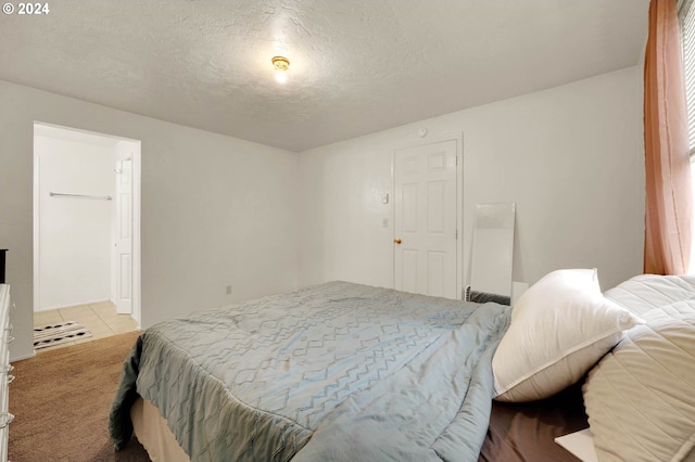 bedroom featuring a textured ceiling and light colored carpet