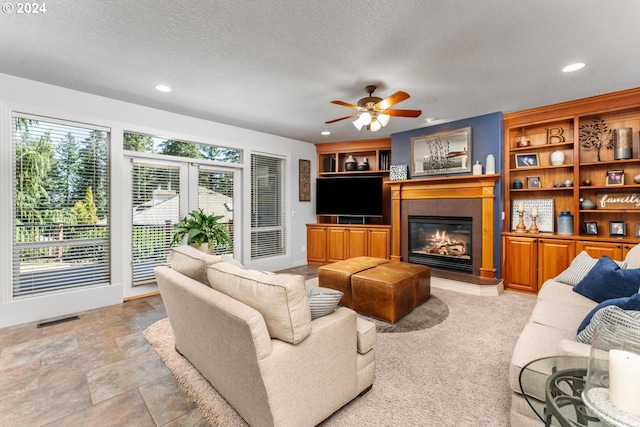 living area featuring recessed lighting, visible vents, a ceiling fan, a glass covered fireplace, and a textured ceiling