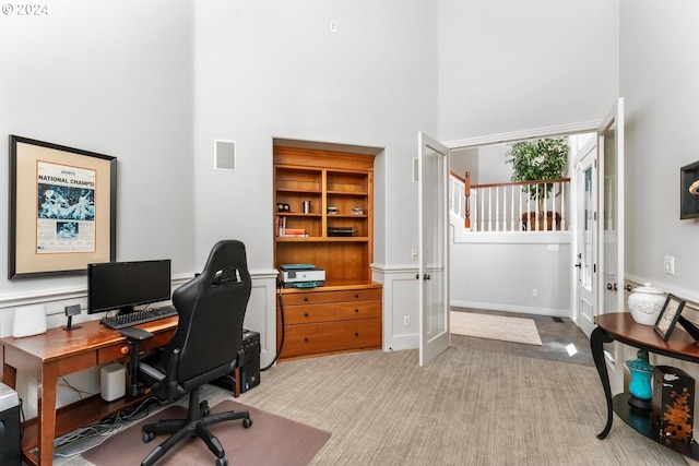 office area with light carpet, a towering ceiling, and visible vents