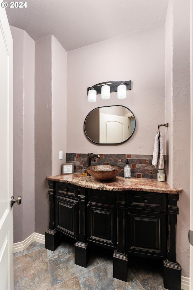 bathroom featuring stone finish flooring, baseboards, and vanity