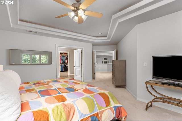 bedroom with light carpet, baseboards, visible vents, a spacious closet, and a tray ceiling