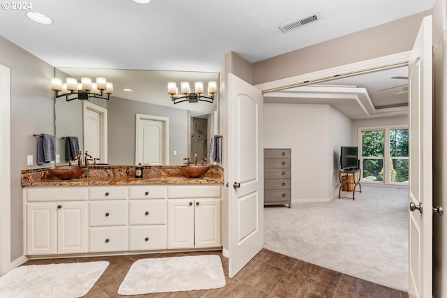 bathroom featuring double vanity, a sink, visible vents, and baseboards