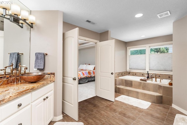 ensuite bathroom with visible vents, a garden tub, a textured ceiling, and ensuite bath