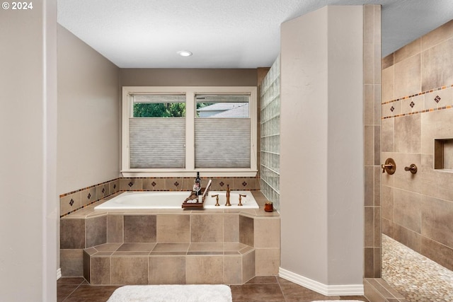 full bathroom featuring a textured ceiling, walk in shower, a bath, and tile patterned floors