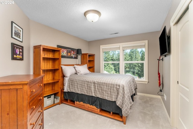 bedroom with light colored carpet, visible vents, baseboards, and a textured ceiling