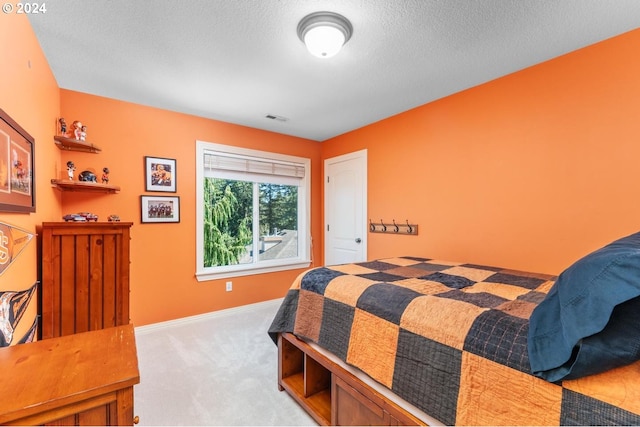 carpeted bedroom with visible vents, a textured ceiling, and baseboards