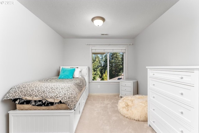 bedroom featuring a textured ceiling, baseboards, visible vents, and light colored carpet