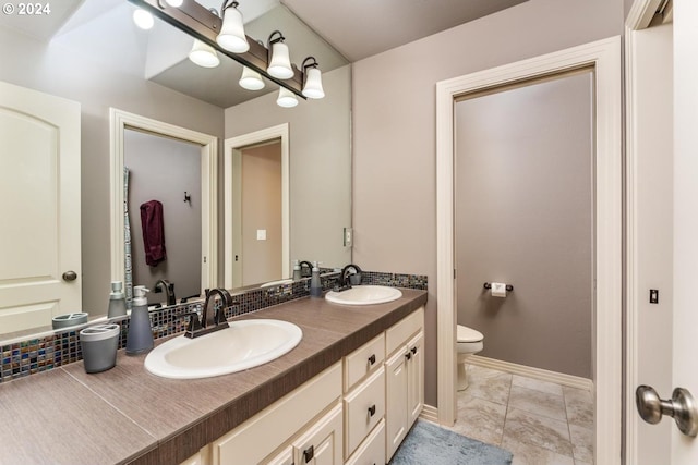 full bath with toilet, double vanity, baseboards, and a sink