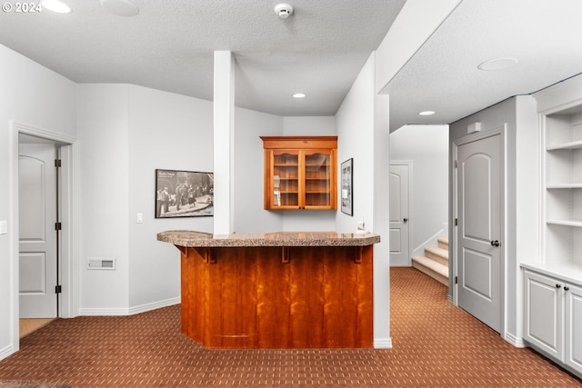 bar with a bar, a textured ceiling, visible vents, and carpet flooring