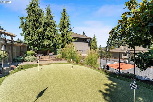 view of property's community featuring a tennis court and fence