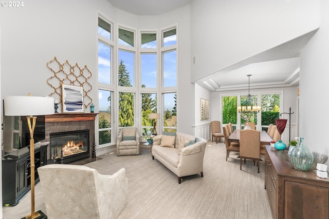 living area with carpet flooring, a fireplace with flush hearth, a towering ceiling, and a notable chandelier