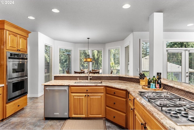 kitchen featuring stainless steel appliances, recessed lighting, a sink, and light stone countertops