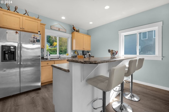 kitchen with a breakfast bar area, light brown cabinets, and stainless steel fridge