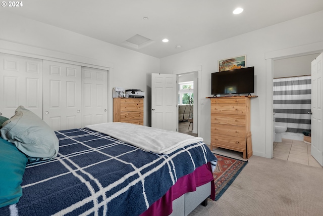 bedroom featuring a closet, ensuite bathroom, and carpet flooring