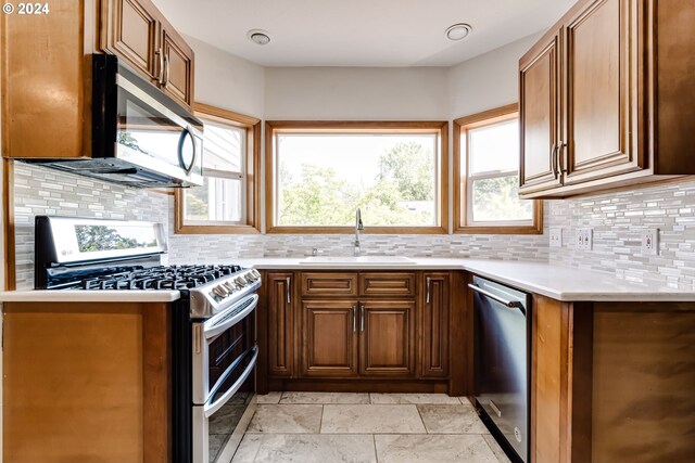 kitchen with a healthy amount of sunlight, appliances with stainless steel finishes, sink, and decorative backsplash