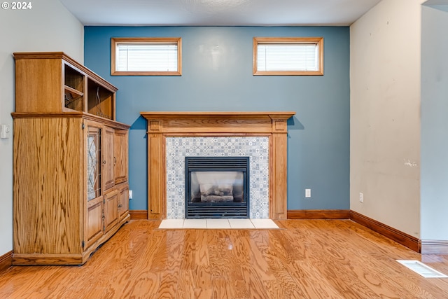 unfurnished living room featuring a tiled fireplace, light hardwood / wood-style flooring, and a wealth of natural light