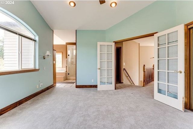 unfurnished bedroom featuring light colored carpet, ensuite bath, and french doors