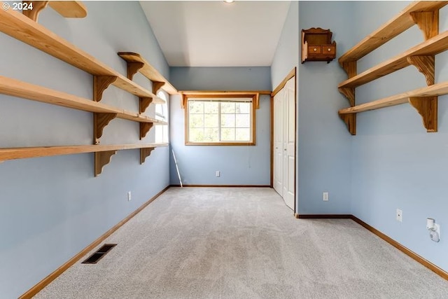 unfurnished bedroom with light colored carpet and a closet