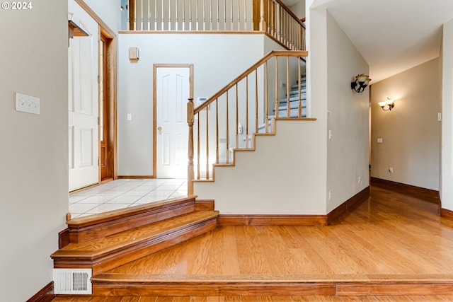 stairs with hardwood / wood-style flooring and a towering ceiling