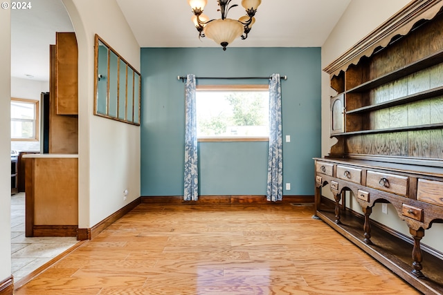 interior space with an inviting chandelier, a wealth of natural light, and light wood-type flooring