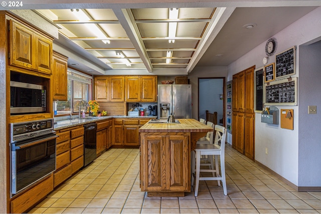 kitchen featuring sink, a kitchen island, light tile patterned flooring, and black appliances