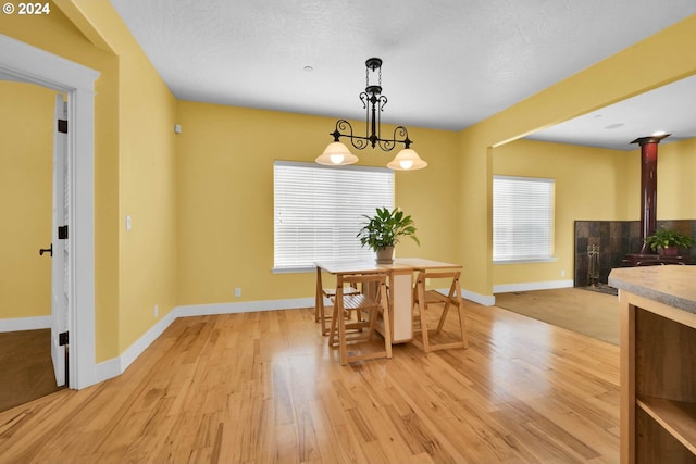 dining space with a textured ceiling, a wood stove, and light wood-type flooring