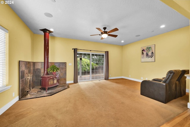 living area with carpet floors, a wood stove, and ceiling fan