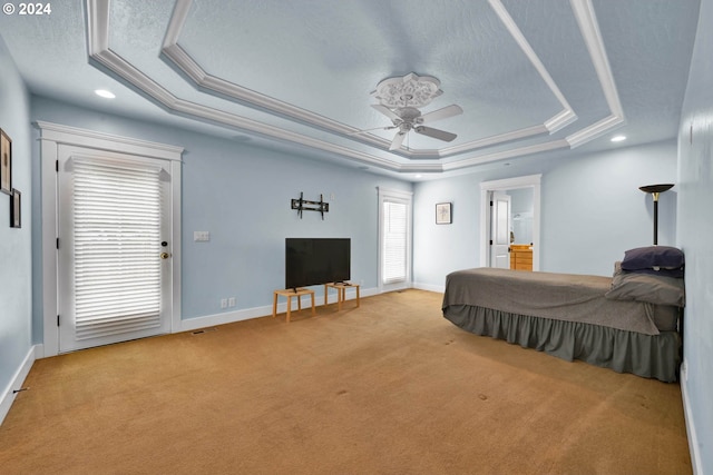 carpeted bedroom featuring ceiling fan, ornamental molding, a tray ceiling, and a textured ceiling