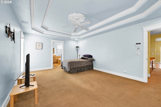 bedroom with ceiling fan, ensuite bathroom, ornamental molding, light carpet, and a raised ceiling