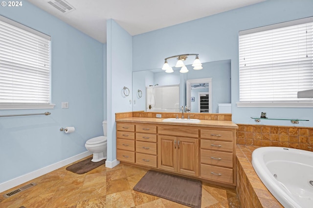 bathroom with a relaxing tiled tub, vanity, and toilet