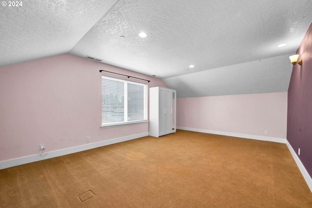 bonus room with light colored carpet, vaulted ceiling, and a textured ceiling